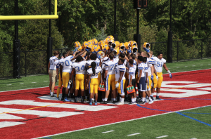 JBS football team huddles before kickoff in the game. 